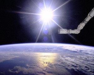 Image of International Space Station's robot arm with sun rising over earth's horizon